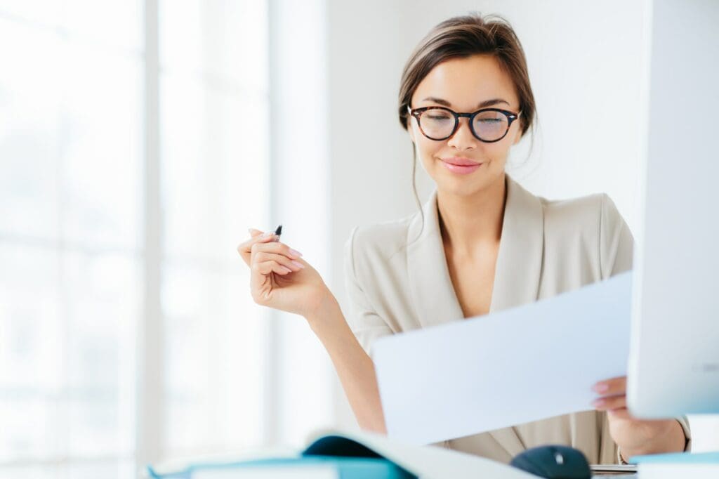 Concentrated successful businesswoman looks attentively in paper, studies terms of contract