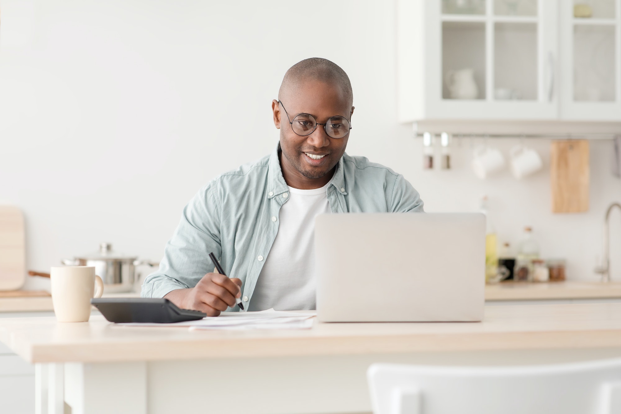 Plan finances. Positive african american mature man calculating taxes and using laptop computer
